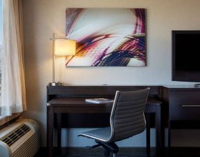 Sonesta San Jose guest room workspace, including desk, chair, lamp, and window, plus TV.