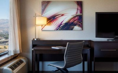 Sonesta San Jose guest room workspace, including desk, chair, lamp, and window, plus TV.
