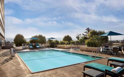 Sonesta San Jose’s outdoor pool has an adjacent hot tub, with tables and chairs, and sun loungers, nearby.