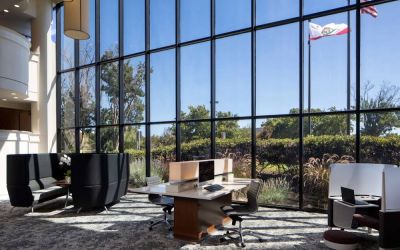 The hotel’s business center has a wall of windows next to it with a view of greenery and flags, while the center itself features multiple workstations and nooks for guests to use.