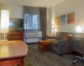 Guest room living area in Sonesta ES Suites Anaheim Resort Area, furnished with sofa and television, plus a workspace desk and chair.