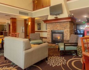 Sonesta ES Suites Anaheim Resort Area’s lobby is furnished with sofa and armchair seating around a widescreen television and fireplace.