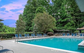 The outdoor pool at Sonesta Charlotte Executive Park has chairs by the side, is close to the fire pit, and connects directly to the indoor pool.