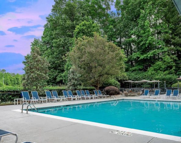 The outdoor pool at Sonesta Charlotte Executive Park has chairs by the side, is close to the fire pit, and connects directly to the indoor pool.