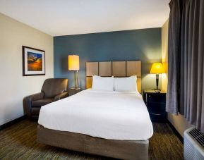 Sonesta Simply Suites St Louis Earth City double bed guest room, featuring bedside lamps, window, and armchair.