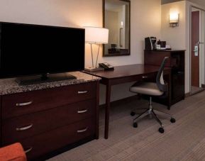 Sonesta Chicago O'Hare Airport Rosemont guest room workspace, including desk, chair, lamp, telephone, and nearby TV.