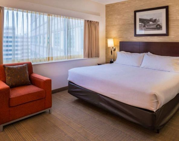 Double bed guest room in Sonesta Chicago O'Hare Airport Rosemont, including window, bedside light, and an armchair.