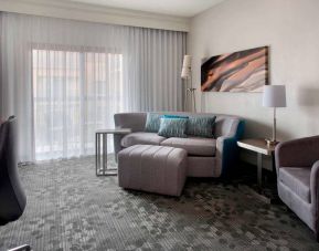 Sonesta Select Newport Middletown guest room living area, furnished with armchair, TV, coffee tables, and a sofa.