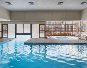 The hotel’s indoor pool has an adjacent hot tub and large windows, with a direct water link to the outdoor pool. 