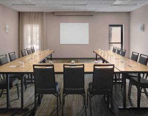 Meeting room in Sonesta Select Newport Middletown, with tables arranged in a U-shape facing a large whiteboard.