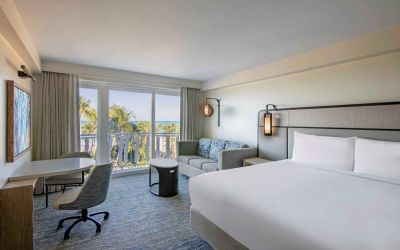 Double bed guest room in Royal Sonesta San Juan, featuring table, chairs, coffee table, and a sofa, plus balcony.