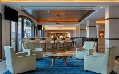 Royal Sonesta San Juan’s lobby lounge has a quartet of armchairs around a coffee table, with a wall-mounted TV and nearby bar.