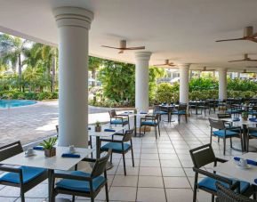 The hotel’s breakfast area has a hard floor, numerous ceiling fans, and small tables within easy reach of the pool.