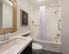 Guest bathroom in Sonesta Simply Suites Jersey City, furnished with bath and shower, lavatory, and sink and mirror.
