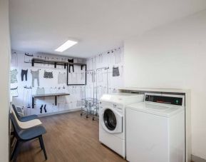 The hotel’s laundry room features a washer and drier, a pair of baskets, plus shelves and chairs.