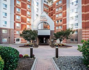 The hotel’s exterior has a brickwork surface, with flowers and trees either side of the entrance, which has the Sonesta Simply Suites name on it.