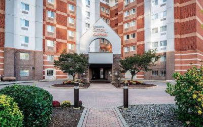 The hotel’s exterior has a brickwork surface, with flowers and trees either side of the entrance, which has the Sonesta Simply Suites name on it.