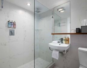 Guest bathroom in Nautilus by Sonesta, including shower, sink, mirror, and lavatory.