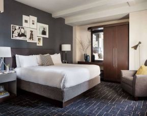 Double bed guest room in The Shelburne Sonesta New York, furnished with bedside lamp, wardrobe, and armchair.