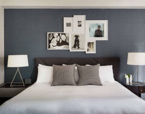 The Shelburne Sonesta New York double bed guest room, with art on the walls and bedside lamps.