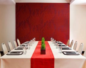 Meeting room in The Shelburne Sonesta New York, furnished with long table, 10 chairs around it, and a stark white and red color scheme.