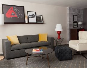 The Fifty Sonesta Select New York guest room living area, furnished with sofa, chair, coffee table, and artwork.