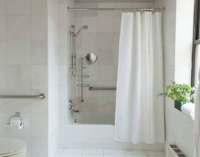 Guest bathroom in The Benjamin Royal Sonesta New York, featuring bath, shower, lavatory, and a small potted plant.