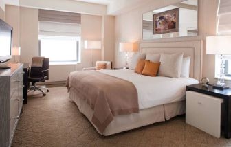 The Benjamin Royal Sonesta New York double bed guest room, including TV, chair, armchair, and window.