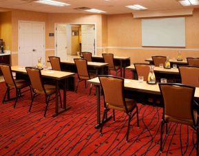 Hotel meeting room, with seating for a dozen attendees, and tables arranged in a classroom format facing a whiteboard.