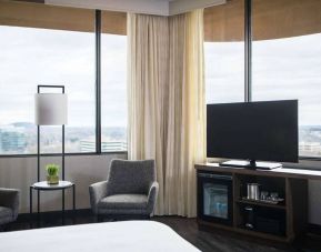 Sonesta Nashville Airport guest room, featuring widescreen television, chairs and a coffee table, and large windows.