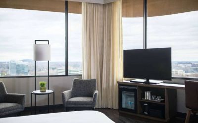 Sonesta Nashville Airport guest room, featuring widescreen television, chairs and a coffee table, and large windows.