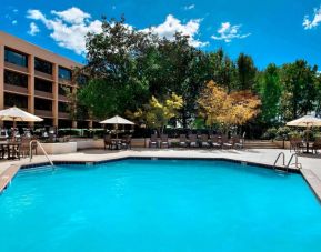 Sonesta Nashville Airport’s outdoor pool has shaded tables and chairs nearby, alongside a row of sun loungers.