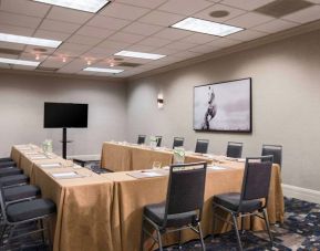 Meeting room in with tables arranged in a U-shape facing  large TV, plus a large artistic photograph of a horse on the wall.