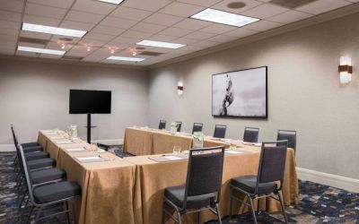 Meeting room in with tables arranged in a U-shape facing  large TV, plus a large artistic photograph of a horse on the wall.