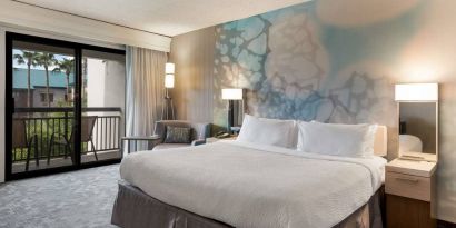 Double bed guest room in Sonesta Select Tempe Downtown, featuring armchair, coffee table, and balcony.