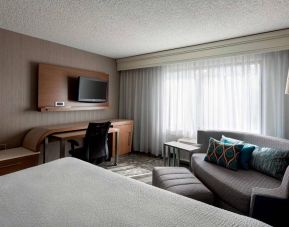 Sonesta Select Tempe Downtown double bed guest room, furnished with TV and sofa, plus workspace desk and chair.