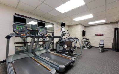 The fitness center in Sonesta Select Tempe Downtown has a wall-mounted TV, free weights, and exercise machines facing a large mirror.