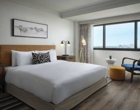 Double bed guest room in Sonesta Irvine, featuring art on the wall, chair, and window.