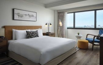 Double bed guest room in Sonesta Irvine, featuring art on the wall, chair, and window.