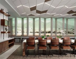 Hotel meeting room, including long table, high ceiling, large windows, and a wall-mounted television.