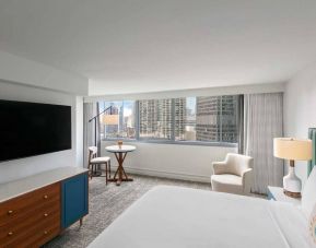 Double bed guest room in Royal Sonesta Chicago Downtown, featuring city views, an armchair, and a large, wall-mounted television.