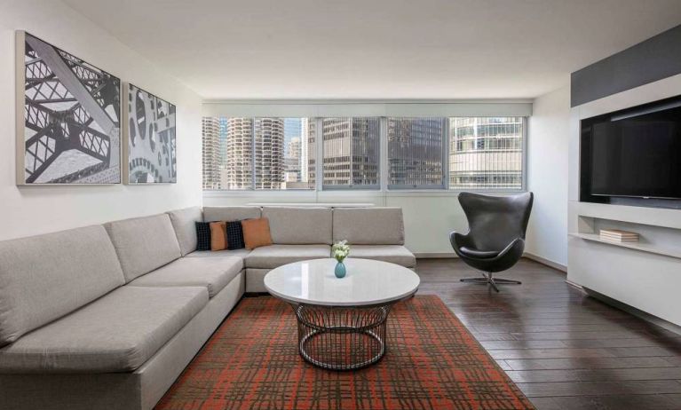 Royal Sonesta Chicago Downtown guest room lounge, with large sofa, chair, and coffee table, plus a wall-mounted TV.