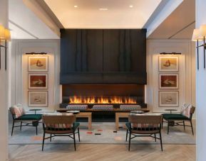 The lobby lounge of Royal Sonesta Chicago Downtown is furnished with comfortable seats and coffee tables close to a fireplace, with art on the walls.