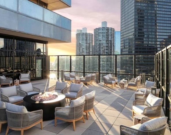 The hotel terrace offers elevated city views and comfy seating beside coffee tables, plus a fire pit.