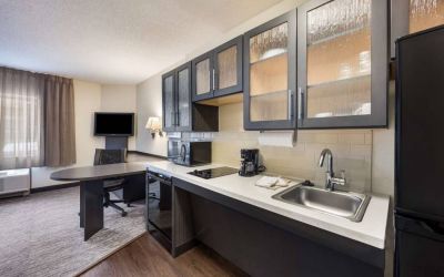 Sonesta Simply Suites Phoenix Tempe guest room kitchen, with hob, microwave, oven, and fridge-freezer, and a nearby TV.