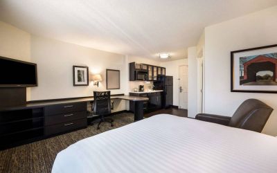 Sonesta Simply Suites Phoenix Tempe double bed guest room, furnished with TV and armchair, plus a workspace desk and chair.