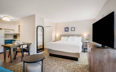Double bed guest room in Sonesta ES Suites Denver South - Park Meadows, with TV and kitchen, between which is a table and chairs.
