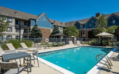 The hotel’s outdoor pool features tables and chairs, with shade available, and sun loungers by the side, with greenery beyond the fence.