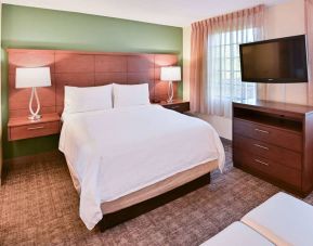 Double bed guest room in Sonesta ES Suites Fort Lauderdale Plantation, featuring bedside lamps, windows, and a large TV.