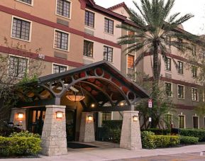 The hotel’s exterior features a covered entrance beside which there’s extensive greenery, including a towering palm tree.